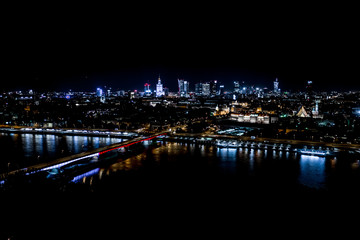 Fototapeta na wymiar Night city skyline background. Aerial view of Warsaw capital city of Poland. From above, night city view with night sky. Night panorama of Warsaw cityscape. Aerial View