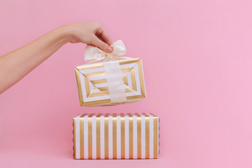 Womans hands holding gift or present box on pink pastel background.