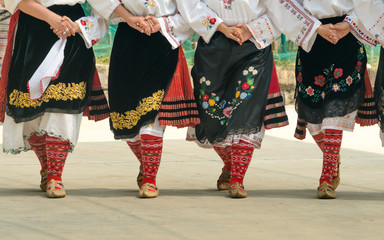 Girls dancing folk dance. People in traditional costumes dance Bulgarian folk dances. Close-up of...