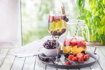 White wine sangria or punch with berries and ice in glass and pincher. Homemade refreshing fruit sangria.