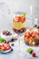 White wine sangria or punch with berries and ice in glass and pincher. Homemade refreshing fruit sangria.