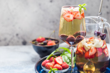 White wine sangria or punch with berries and ice in glass and pincher. Homemade refreshing fruit sangria.