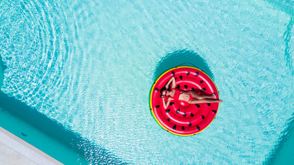 Summer Vacation. Enjoying woman in bikini on the inflatable mattress in the swimming pool.