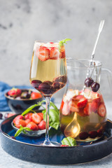 White wine sangria or punch with berries and ice in glass and pincher. Homemade refreshing fruit sangria.