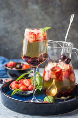 White wine sangria or punch with berries and ice in glass and pincher. Homemade refreshing fruit sangria.