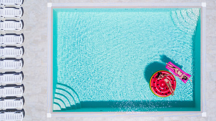 Aerial view of two women floating on inflatable mattresses relaxing in the swimming pool. Summer...
