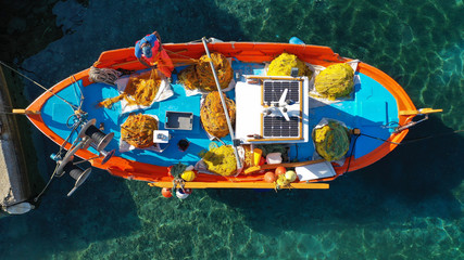 Fototapeta na wymiar Aerial drone top view photo of traditional colourful fishing boat near iconic beach of Ornos with emerald clear sea, Mykonos island, Cyclades, Greece