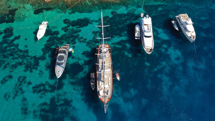 Aerial drone photo of luxury yachts docked in famous turquoise clear sea bay of Ornos, Mykonos island, Cyclades, Greece