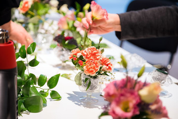 Closeup of hands of young woman florist creating bouquet of pink flowers on the table