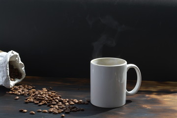 cup of coffee in white cup and beans on wooden table black background