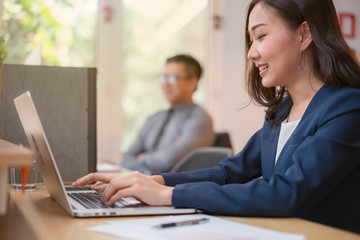 Fototapeta premium Asian woman office worker is working on a laptop with enjoy and happy in the office.