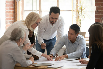 Diverse business team young and old workers brainstorm on paperwork