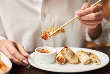 Close up of woman eating tasty dinner in luxury restaurant. Delicious dinner from soup with seeds, tempura shrimps and noodles with vegetables preparing for female client.