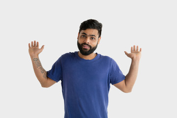 Fototapeta premium Beautiful male half-length portrait isolated on white studio background. Young emotional hindu man in blue shirt. Facial expression, human emotions, advertising concept. Presenting and inviting.