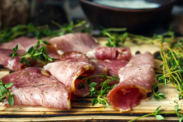 delicious pork bacon sliced ​​into strips on a wooden background with spices and fresh thyme. A serving of low-fat succulent farm meat pork. Food Photography