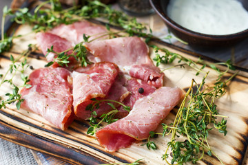 Delicious flavorful ham sliced ​​into strips on a wooden background with spices and fresh thyme. A serving of low-fat succulent farm meat pork. meat product. Food Photography