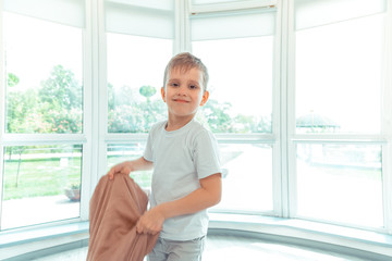 Happy cute boy standing in front of the window