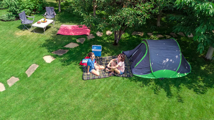 Aerial top view of campsite from above, mother and daughter having fun, tent and camping equipment under tree, family vacation in camp outdoors concept  © Iuliia Sokolovska