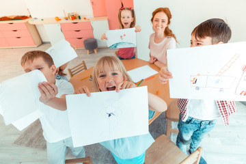 Top view of happy positive children with drawings