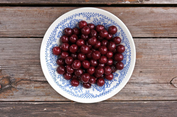Ripe cherry in a plate on a wooden table
