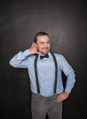 Handsome business man with call gesture on blackboard
