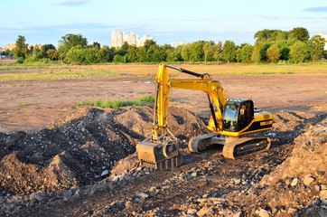Large tracked excavator digs the ground for the foundation and construction of a new building in...