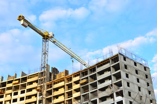 Tower cranes and new residential high-rise buildings at a huge construction site on background blue sky background. Building construction, installation of formwork and concrete structures - Image