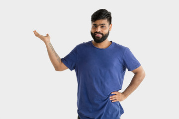 Beautiful male half-length portrait isolated on white studio background. Young emotional hindu man in blue shirt. Facial expression, human emotions, advertising concept. Showing an empty space bar.