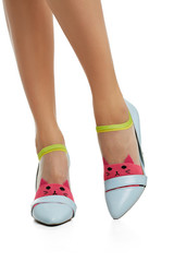 Cropped side shot of female legs in nylon socks, adorned with raspberry red knitted cat's face insertion on toes. The lady is wearing high-heeled light blue shoes, posing on the white background.