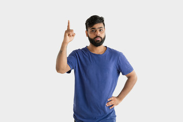 Fototapeta premium Beautiful male half-length portrait isolated on white studio background. Young emotional hindu man in blue shirt. Facial expression, human emotions, advertising concept. Pointing and choosing.