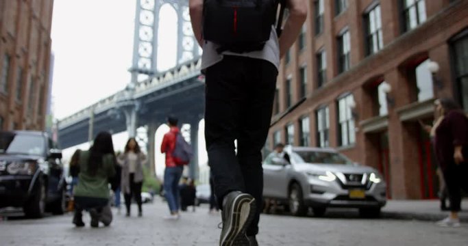 Cultured Man Walking In The Trendy Streets Of Dumbo Brooklyn Towards The Impressive Manhattan Bridge In Iconic New York