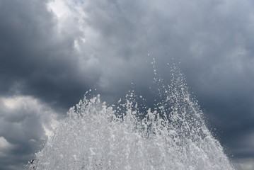 Fountain splashes under cloudy sky