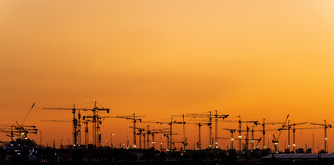 Silhouette of cranes at construction site
