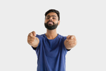 Naklejka premium Beautiful male half-length portrait isolated on white studio background. Young emotional hindu man in blue shirt. Facial expression, human emotions, advertising concept. Pointing and choosing.