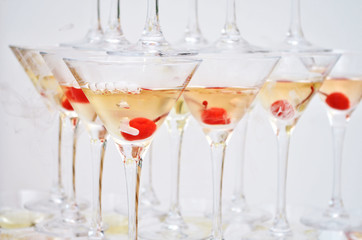 Triangular martini glasses, filled with champagne with cherries and liquid nitrogen, in the shape of a pyramid