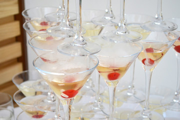 Triangular martini glasses, filled with champagne with cherries and liquid nitrogen, creating steam, shape of a pyramid