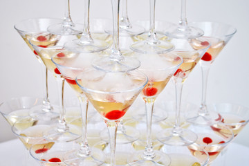 Triangular martini glasses, with cherries and liquid nitrogen, creating steam, built in the shape of a pyramid