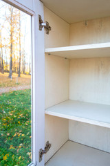 Wooden bookshelf. Empty shelf. Closet with glass door overlooking the nature.