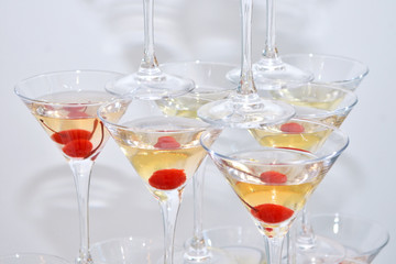 Triangular martini glasses, filled with champagne with cherries built in the shape of a pyramid, top view