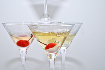 Three martini glasses, with cherries and liquid nitrogen, creating steam, built in the shape of a pyramid