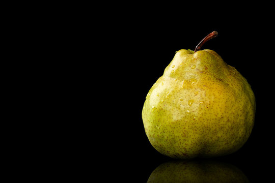 Fresh, organic, ripe, Green Anjou pear with the stem, water drops and reflection on a black background