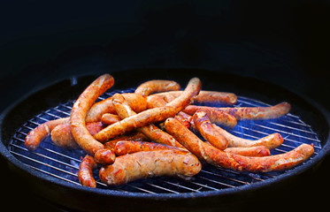 fried hot grilled sausages on a black background