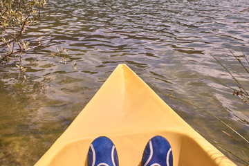 View of a man's feet while kayaking on the river