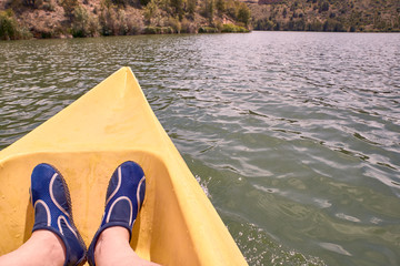 View of a man's feet while kayaking on the river