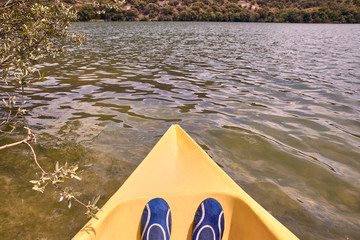 View of a man's feet while kayaking on the river