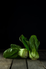 Baby bok choi on wooden rustic background. Vertical mage with copy space.