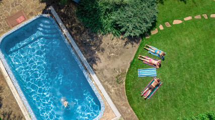 Happy family relaxing by swimming pool, aerial drone view from above of parents and kids have fun on vacation, family weekend on resort