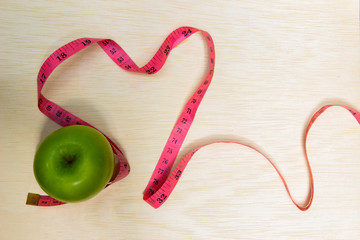 Closeup of green apple and tape wrapping around pink apple on aged wood table background healthy food and concept for diet, Healthcare, Nutrition or medical insurance.