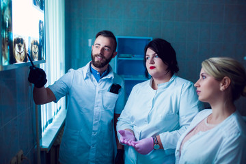 Dental clinic. A group of professional doctors discusses dentistry treatment on x-rays in the...