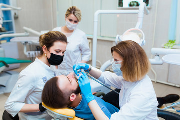 Dental clinic. Professional doctor dentist treats teeth to the patient in the office on modern equipment. Dental insurance.